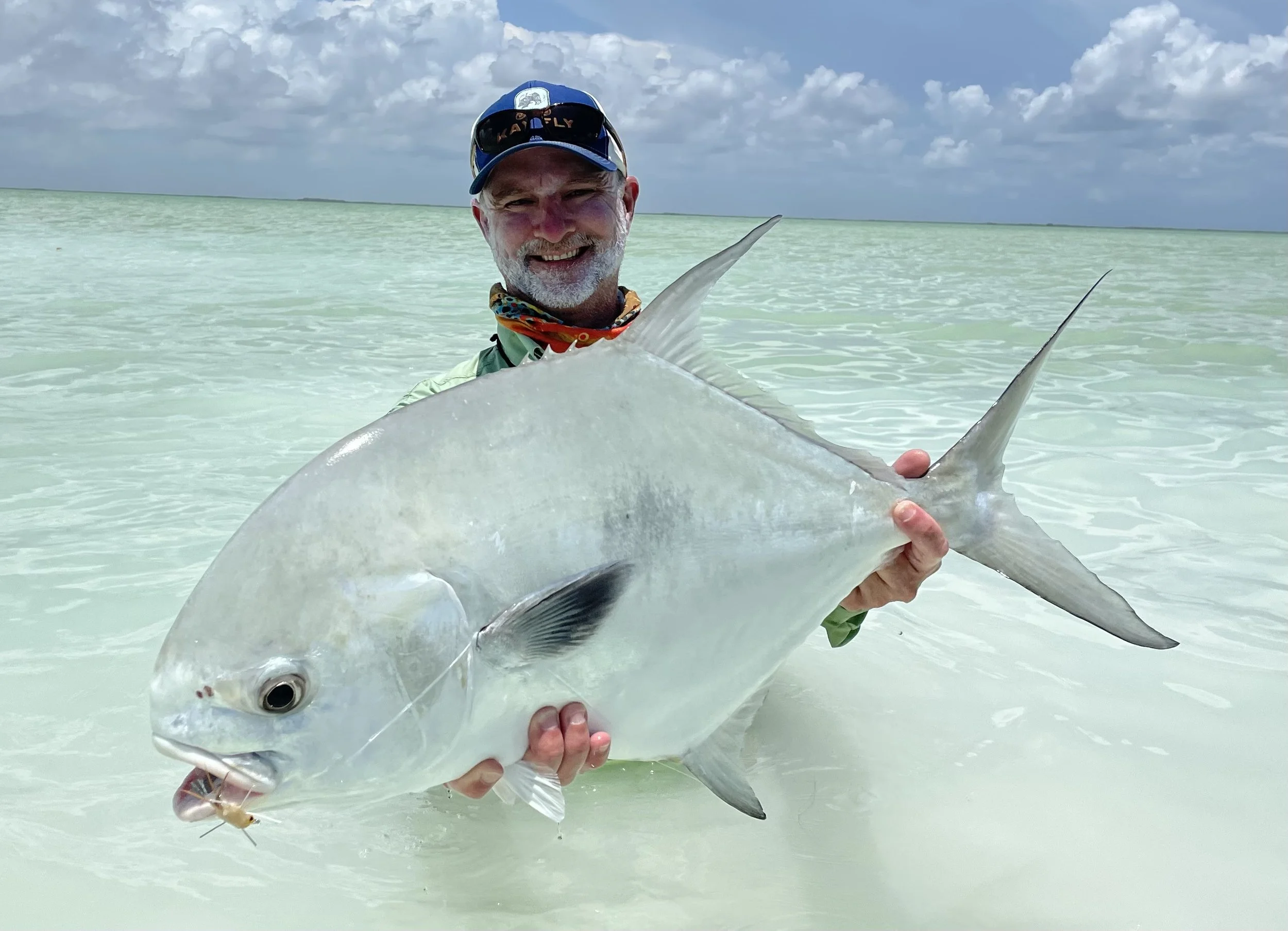 Fly fishing angler holding a trophy permit in the crystal-clear waters of Ascension Bay, Mexico.