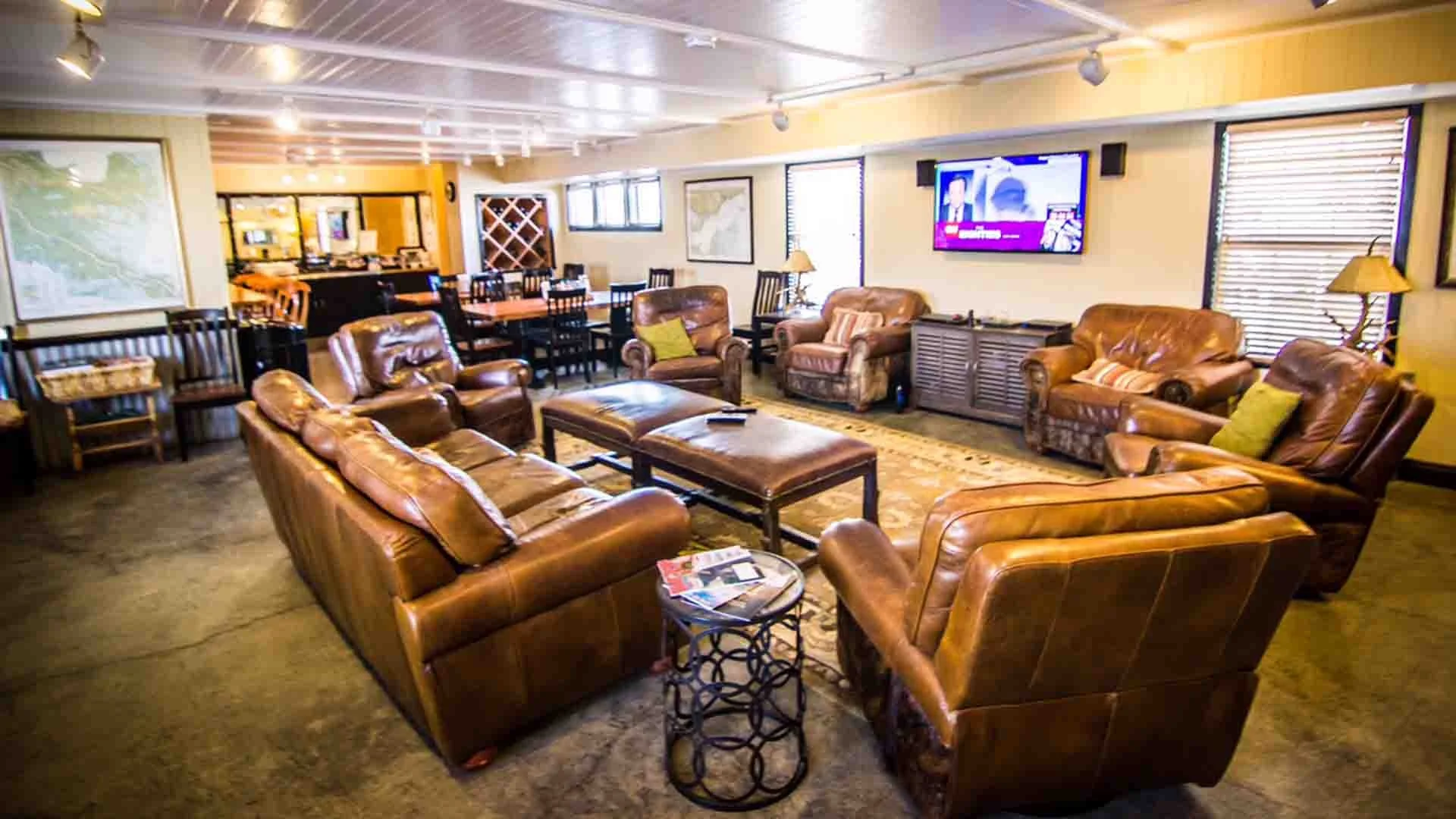 Comfortable lodge lounge area with leather seating and TV, perfect for relaxing after a day of redfishing in Louisiana.
