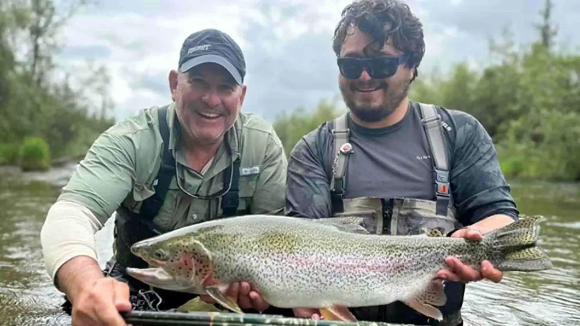 Angler fly fishing for trophy rainbow trout on American Creek in Alaska, surrounded by pristine wilderness