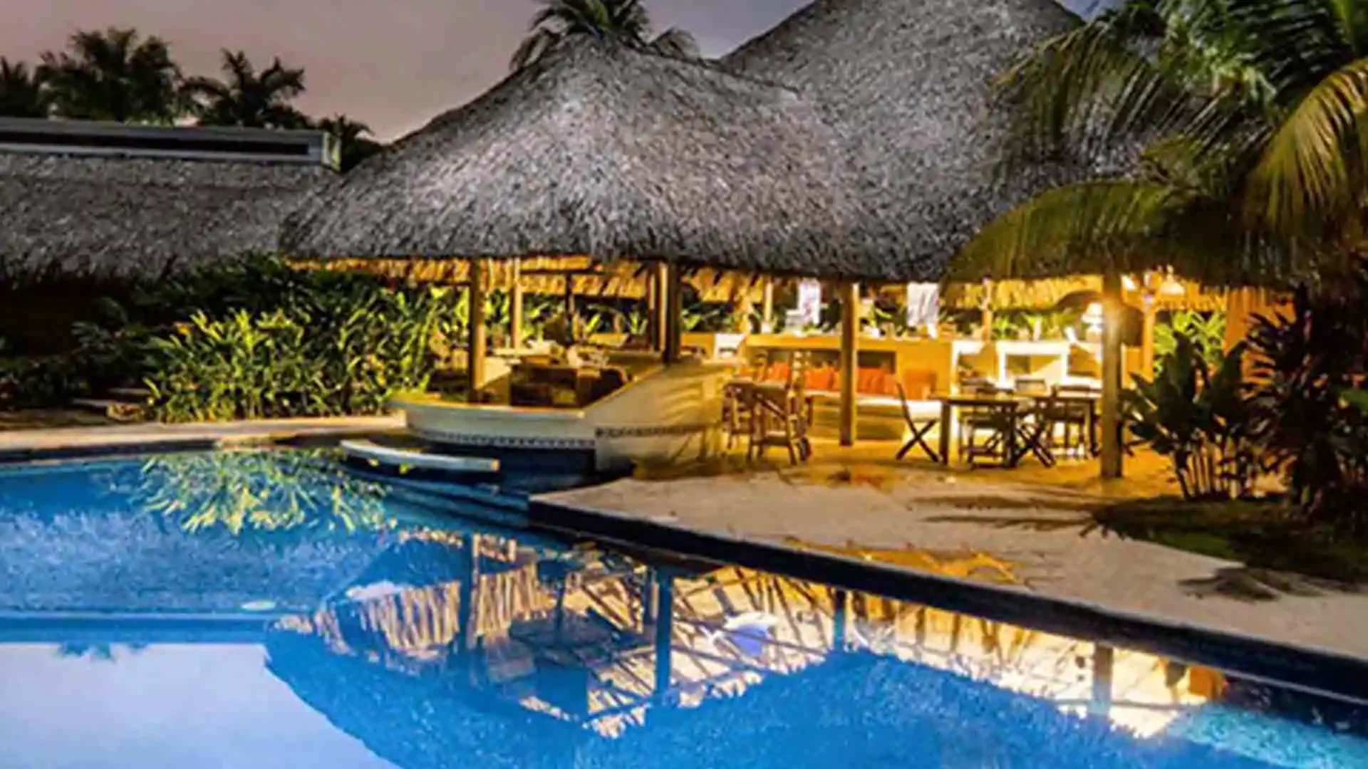 Open-air rancho by the swimming pool at Sailfish Oasis Lodge in the evening, featuring comfortable seating and ambient lighting.