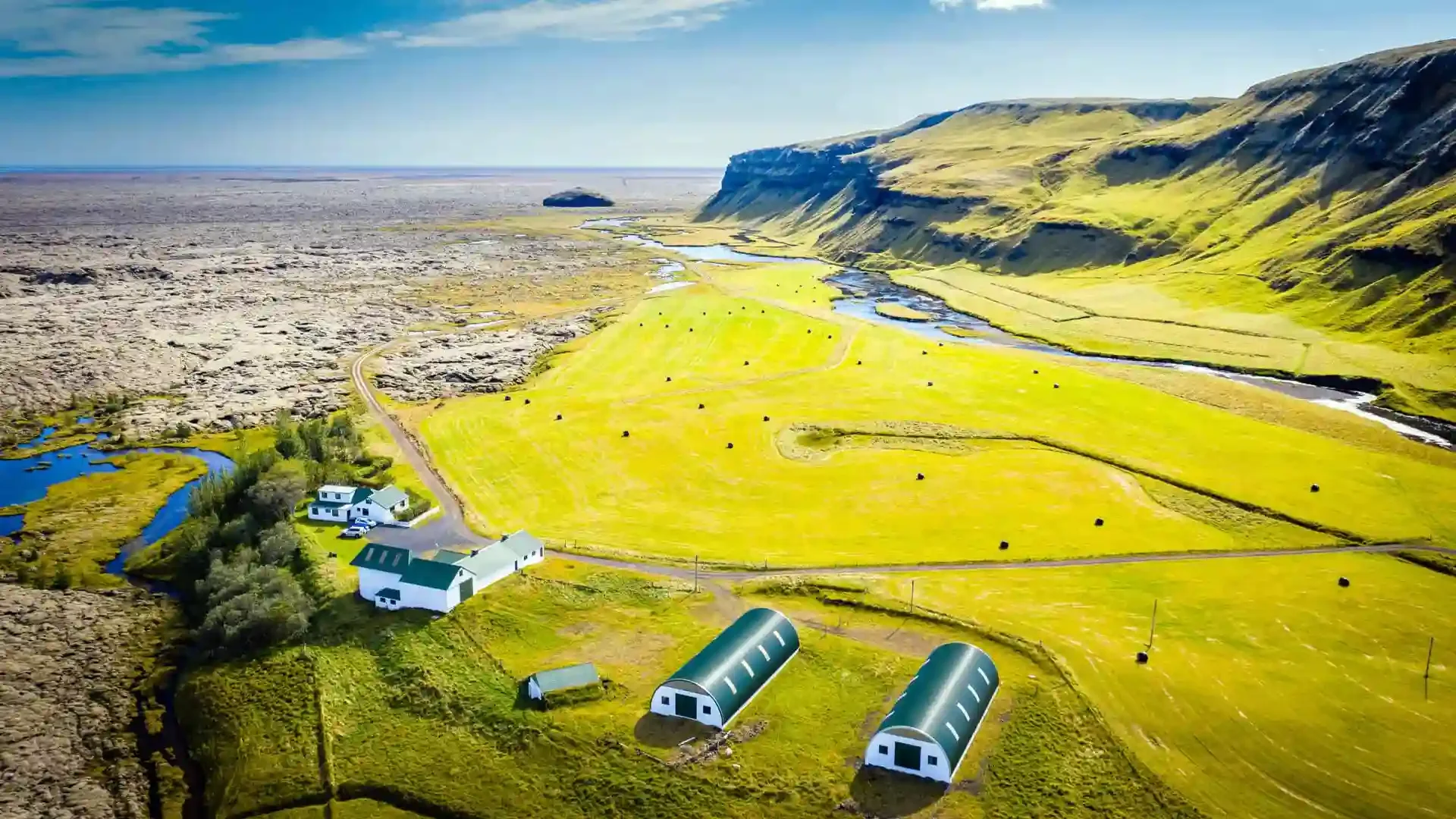 Aerial view near Battle Hill Lodge of a winding Icelandic river through green valleys and mountains.