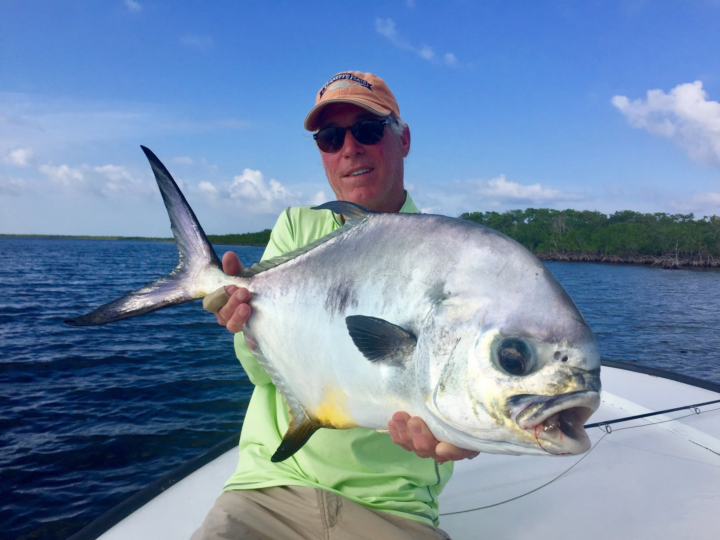 Angler showing a large permit on the Caribbean flats of Turneffe Atoll