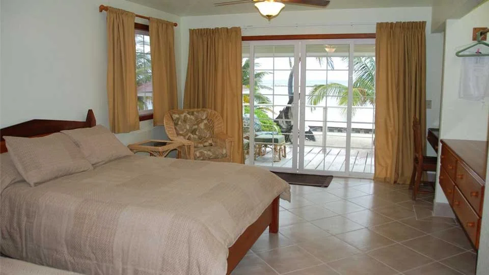 Guest accommodations at Turneffe Flats with comfortable beds and sliding glass doors overlooking the Caribbean Sea