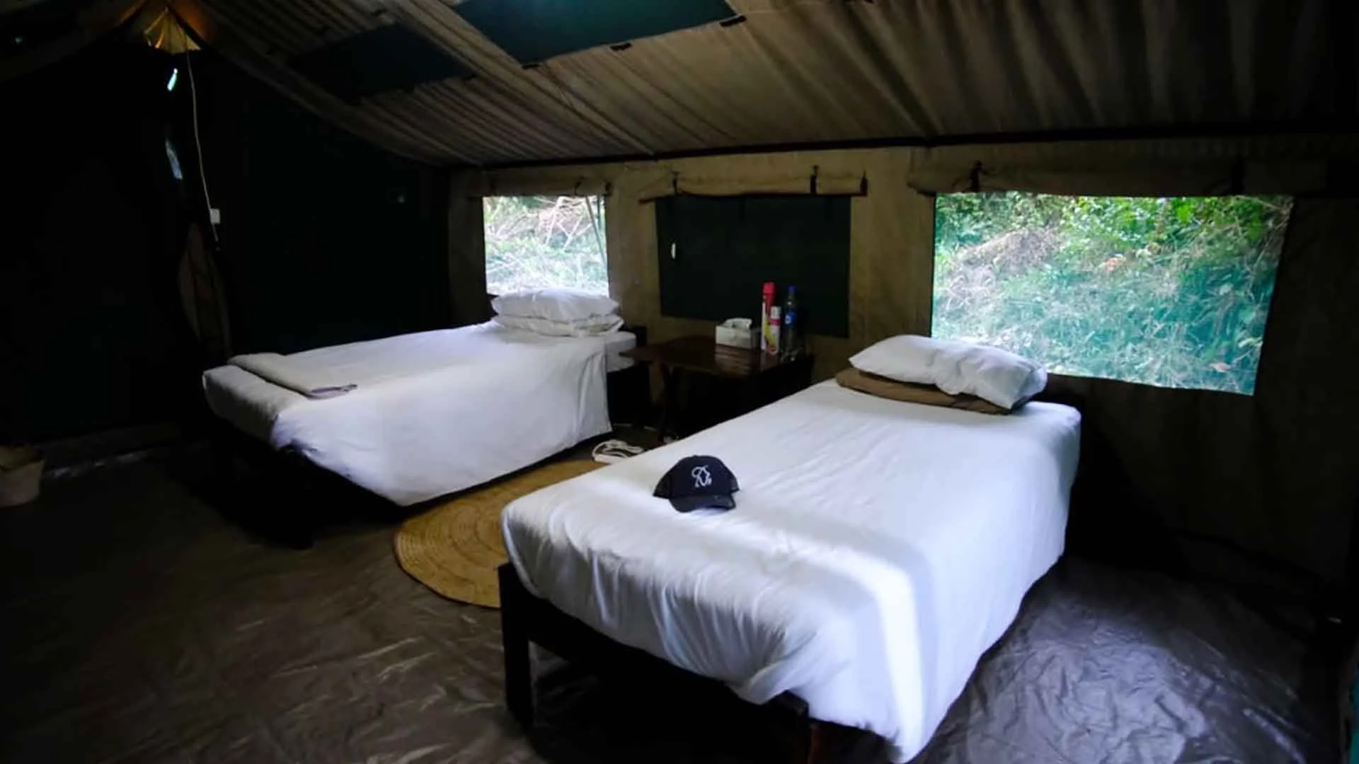 Tanzania safari tent interior with two beds, white linens, and jungle views, ideal accommodation for a tigerfish fishing trip.