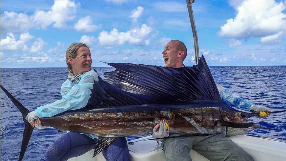 two happy anglers holding sailfish caught at alphonse island lodge seychelles