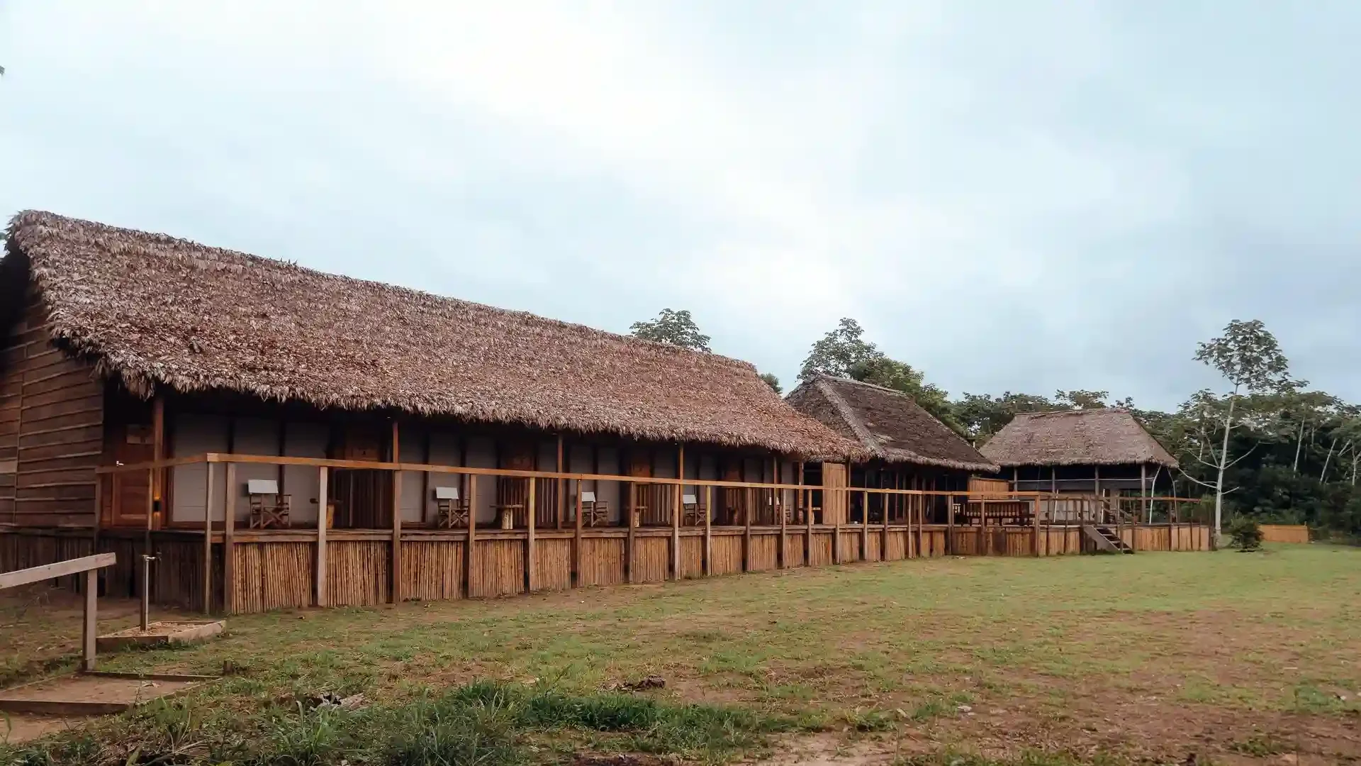 Thatched-roof lodge with wooden walkways at Tsimane fishing camp in Bolivia