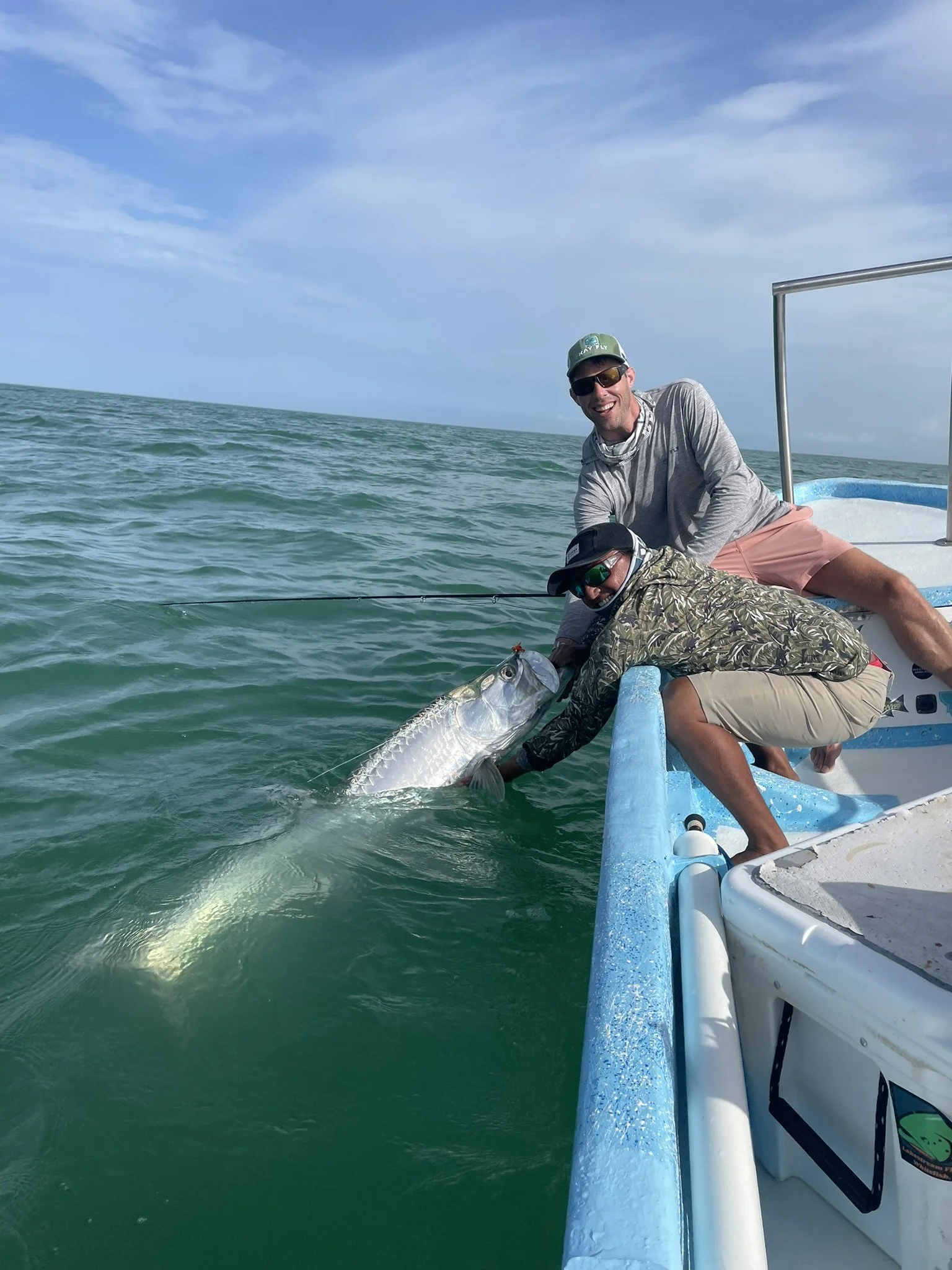 Kay Fly Lodge guide helping an angler hold a large tarpon in the waters of Ascension Bay, both smiling at the camera.