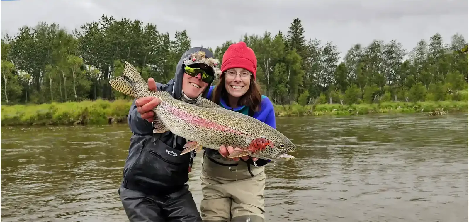 Female angler smiling while holding a trophy Leopard trout caught on the Aniak River in Alaska during a guided fly fishing adventure.