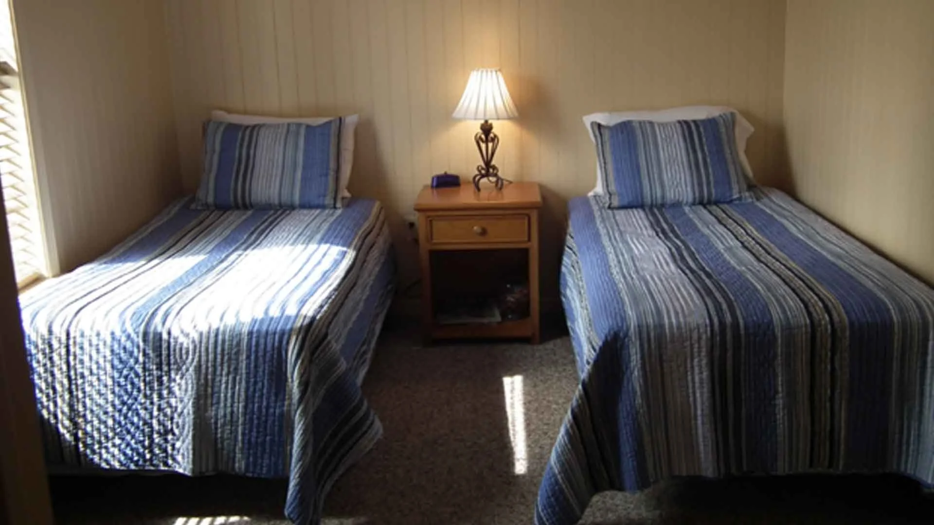 Cozy twin bedroom with striped bedding and nightstand, perfect accommodation for a Louisiana redfishing adventure.