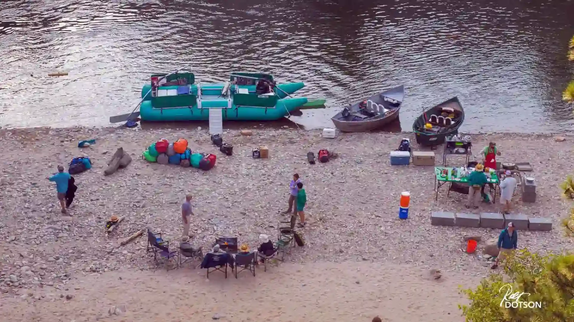 Overhead view of a fly fishing camp on the Middle Fork Salmon River with rafts, drift boats, and people gathered on the rocky bank.