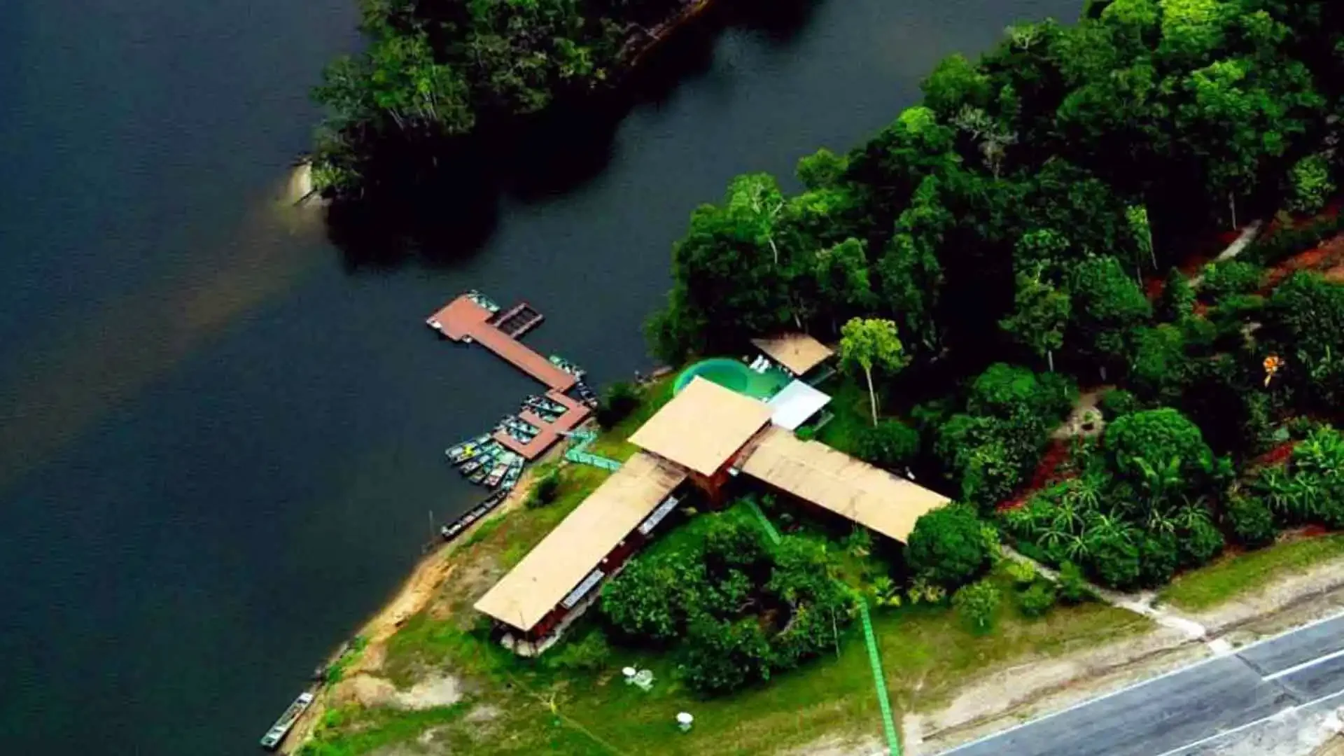 Aerial view of Itapará Lodge in Brazil, a fly fishing destination on a jungle river with docks and boats.