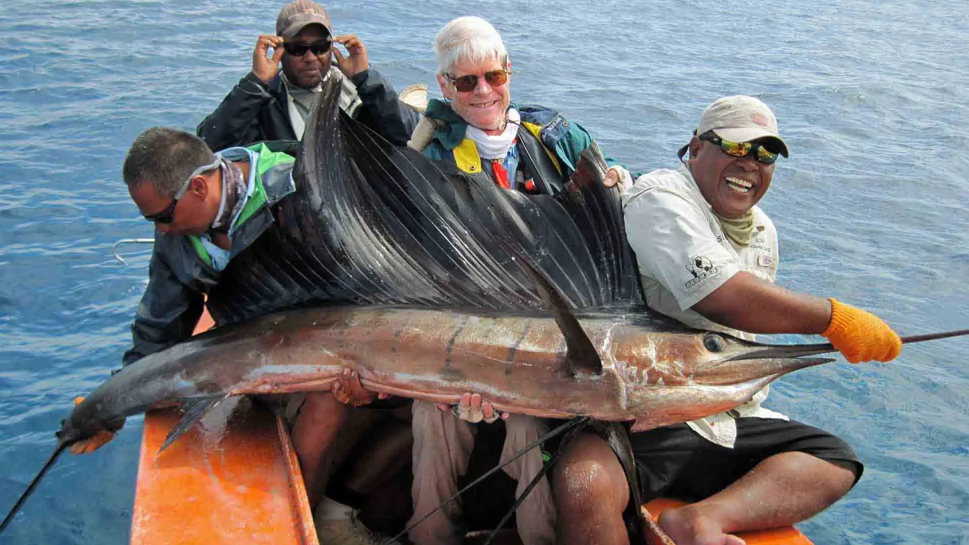 Anglers and guide trying to hoist a large sailfish into the boat while fishing on Christmas Island, Kiribati