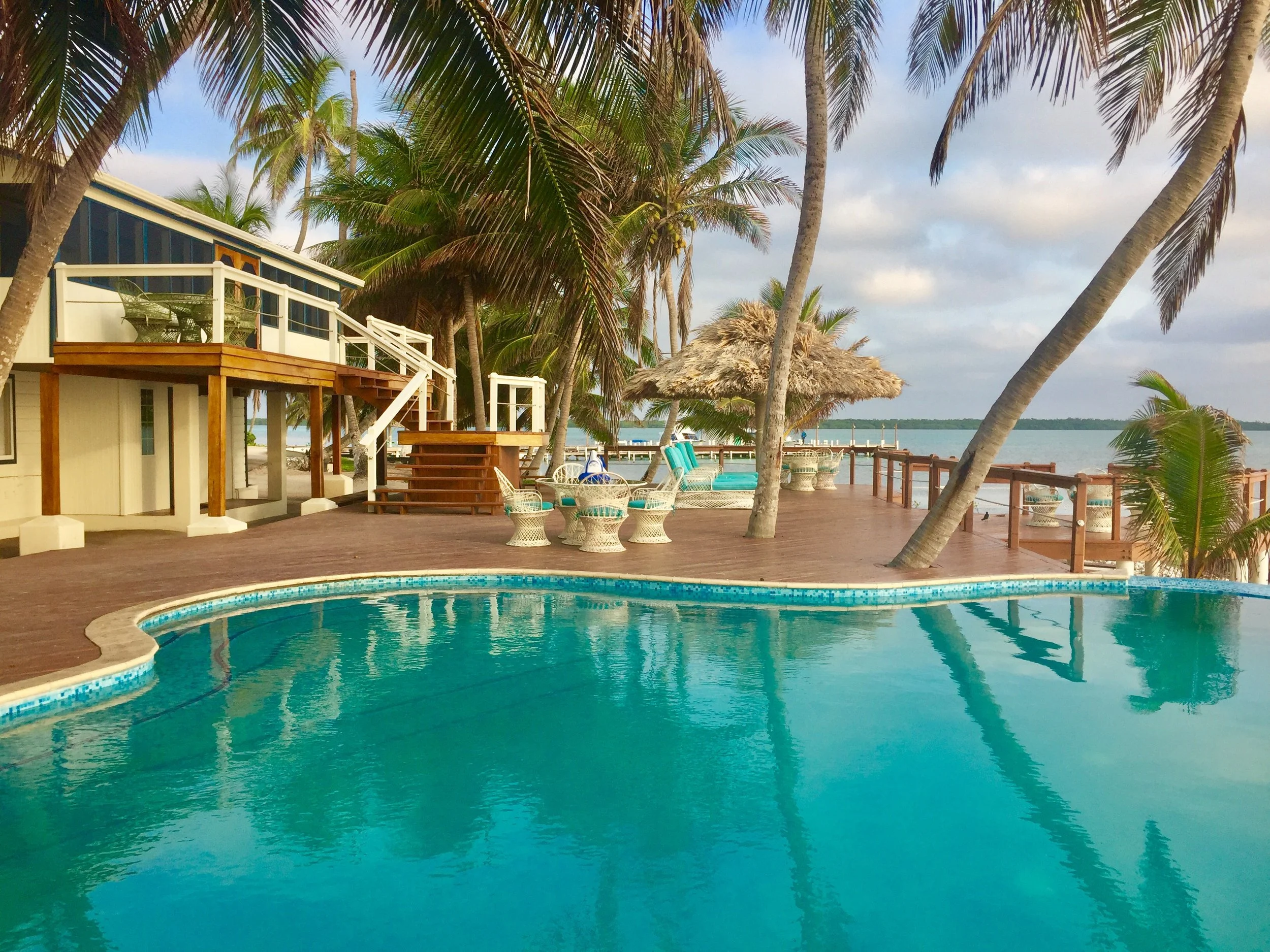 Main lodge and swimming pool at Turneffe Flats Resort surrounded by palm trees and Caribbean waters in Belize