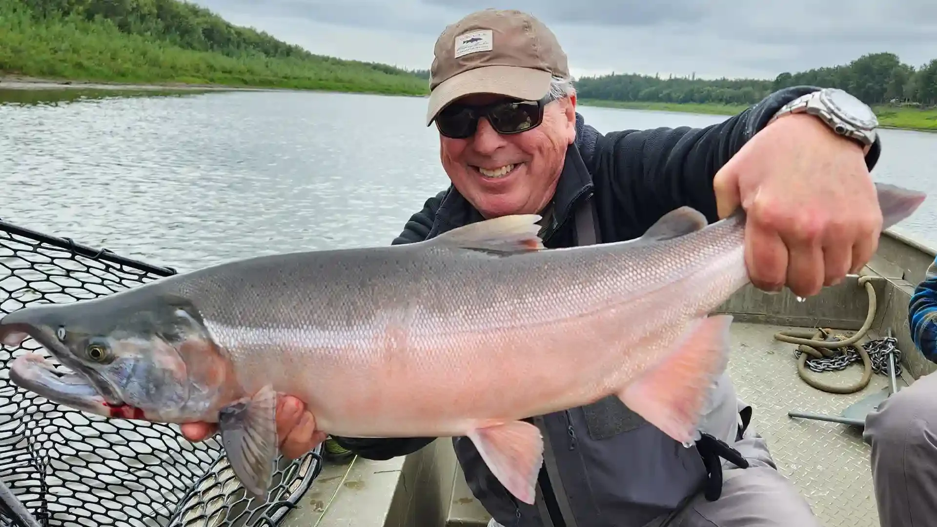 Angler holding a trophy Coho (Silver) Salmon caught on the Aniak River in Alaska during a guided fly fishing trip with Aniak River Lodge