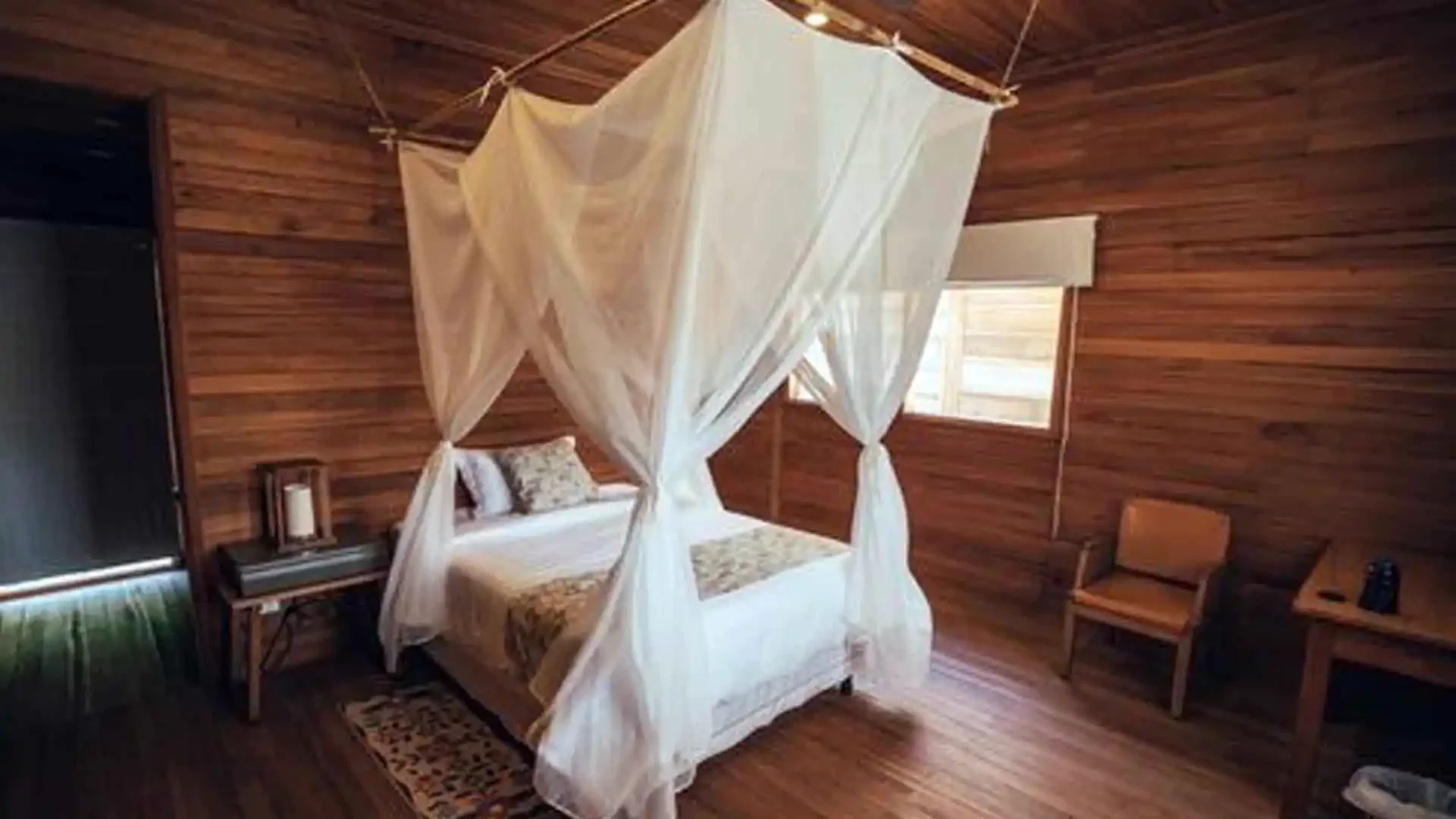 Guest room at Tsimane Pluma Lodge with queen bed, mosquito netting, and native wooden furnishings in the Bolivian jungle