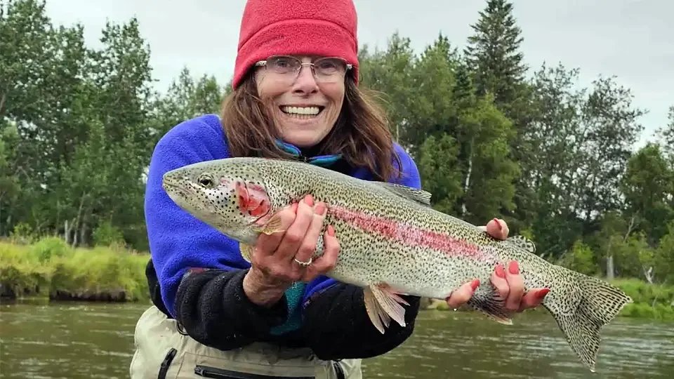 Female angler smiling while holding a trophy Leopard trout caught on the Aniak River in Alaska during a guided fly fishing adventure.