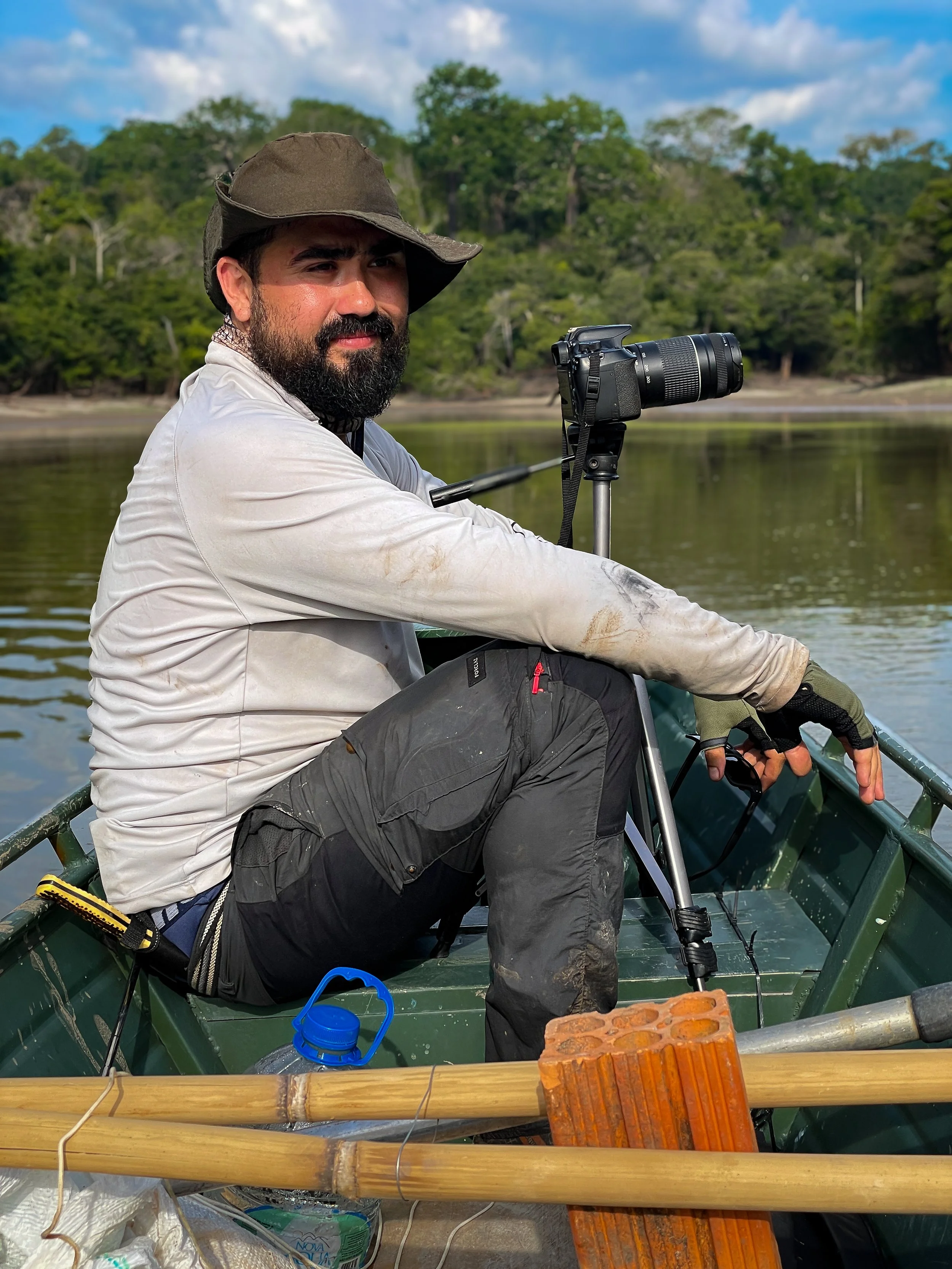 Person in a boat with camera tripod and nature background