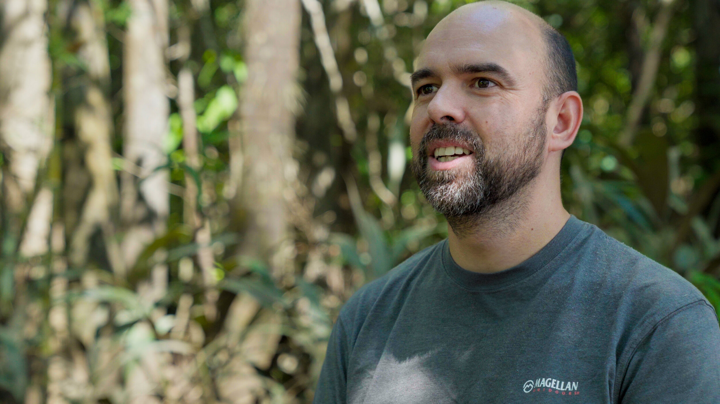 Man with a beard smiling in a forest