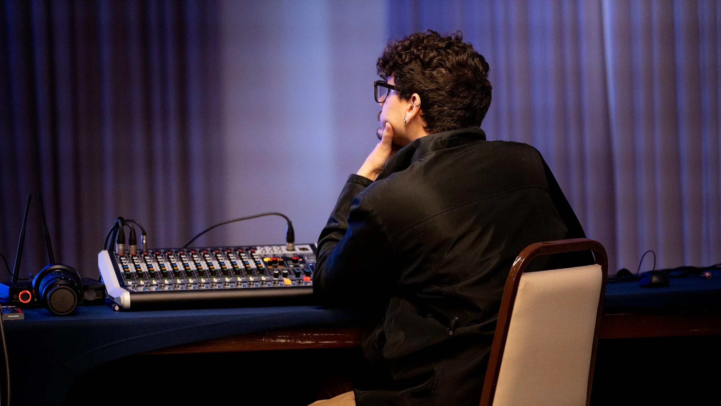 Person operating a mixing console with headphones on a table