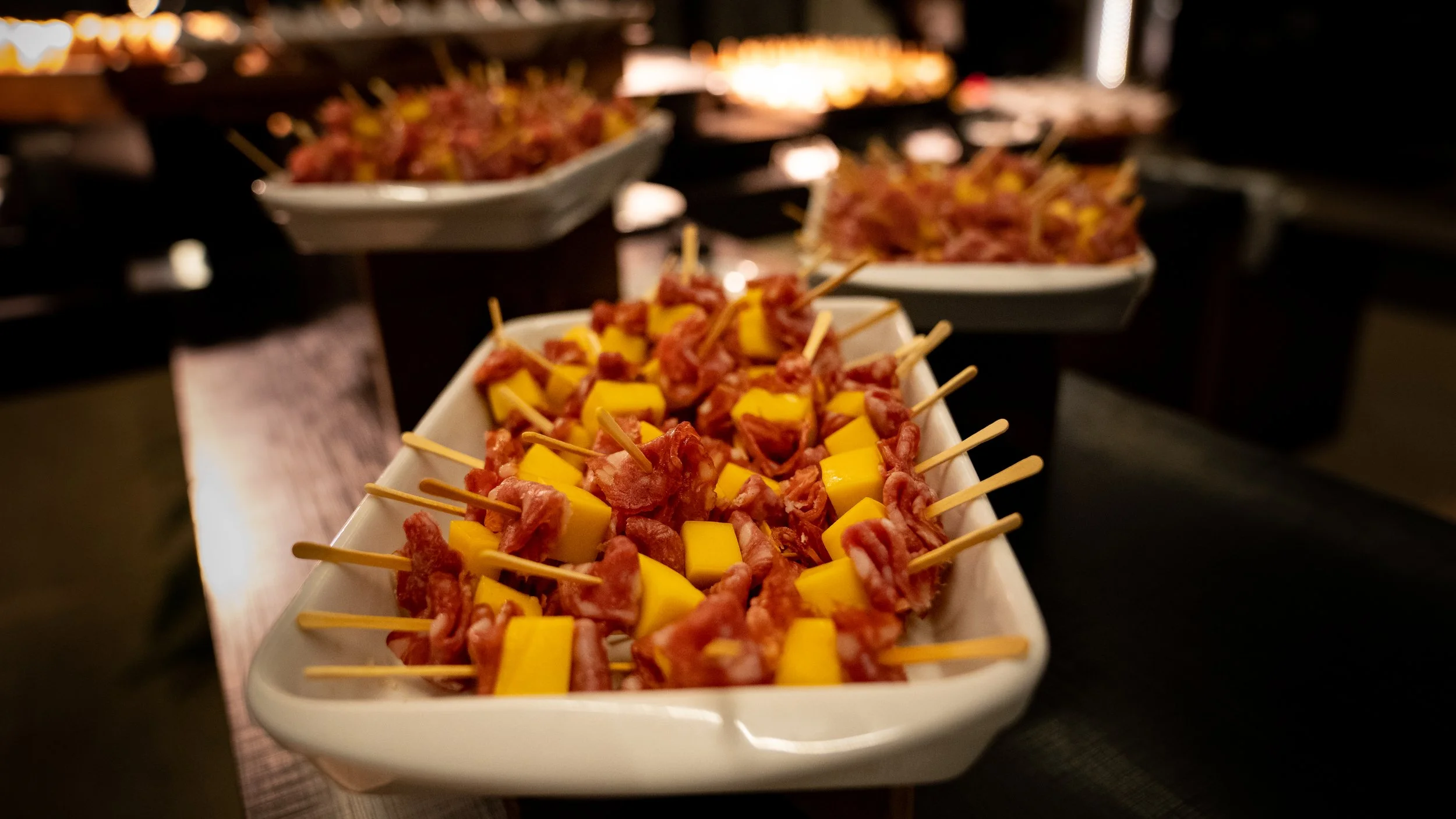 Appetizer skewers with salami and cheese on a white platter