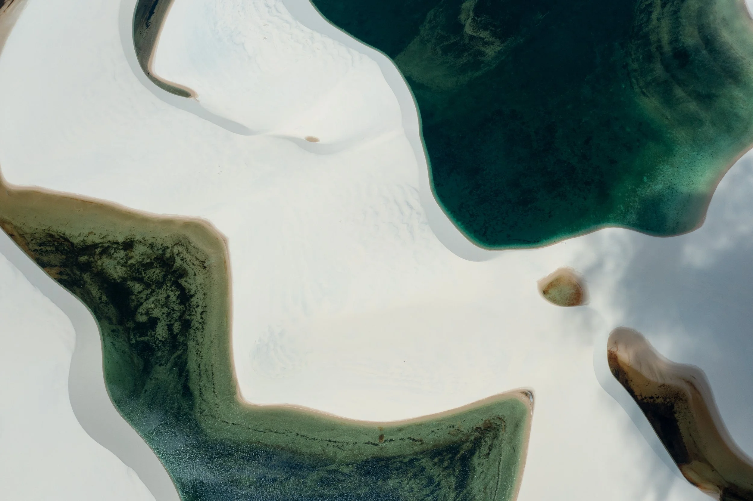 Close-up of a marble or natural stone sculpture with smooth, flowing shapes and shades of white, green, and brown.