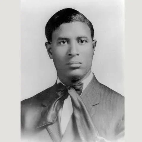 Black and white portrait of a young man in a suit with a bow tie.