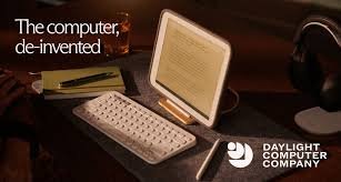 A vintage computer setup with a monitor, keyboard, and a white mobile device, with text that says 'The computer, de-invented.' in a dimly lit environment. The logo of Daylight Computer Company is in the bottom right corner.