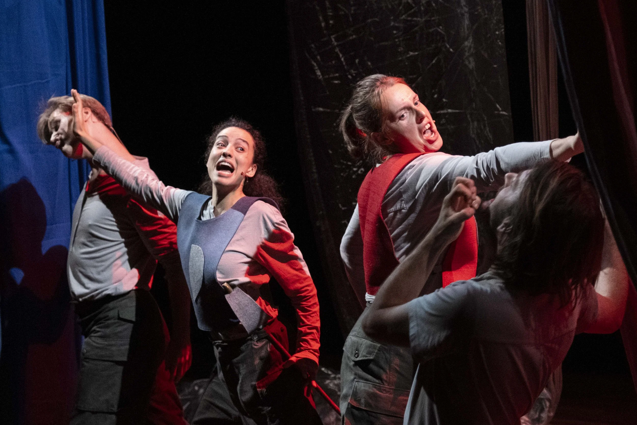 Four actors on stage in a theatrical performance, expressing intense emotions, with dramatic facial expressions and body language.