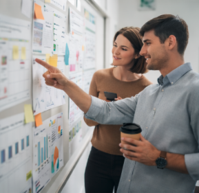 Two professionals discussing data on a whiteboard in a modern office.