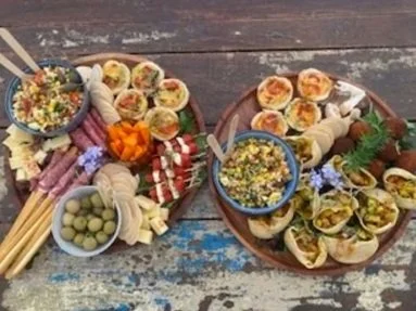 Charcuterie boards with assorted cheeses, meats, vegetables, and dips on a rustic wooden table.
