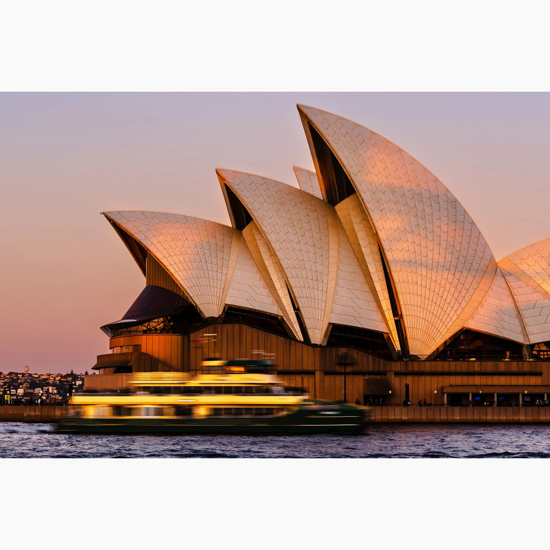 Sydney Opera House at sunset with a passing ferry blurred in motion across the harbour.