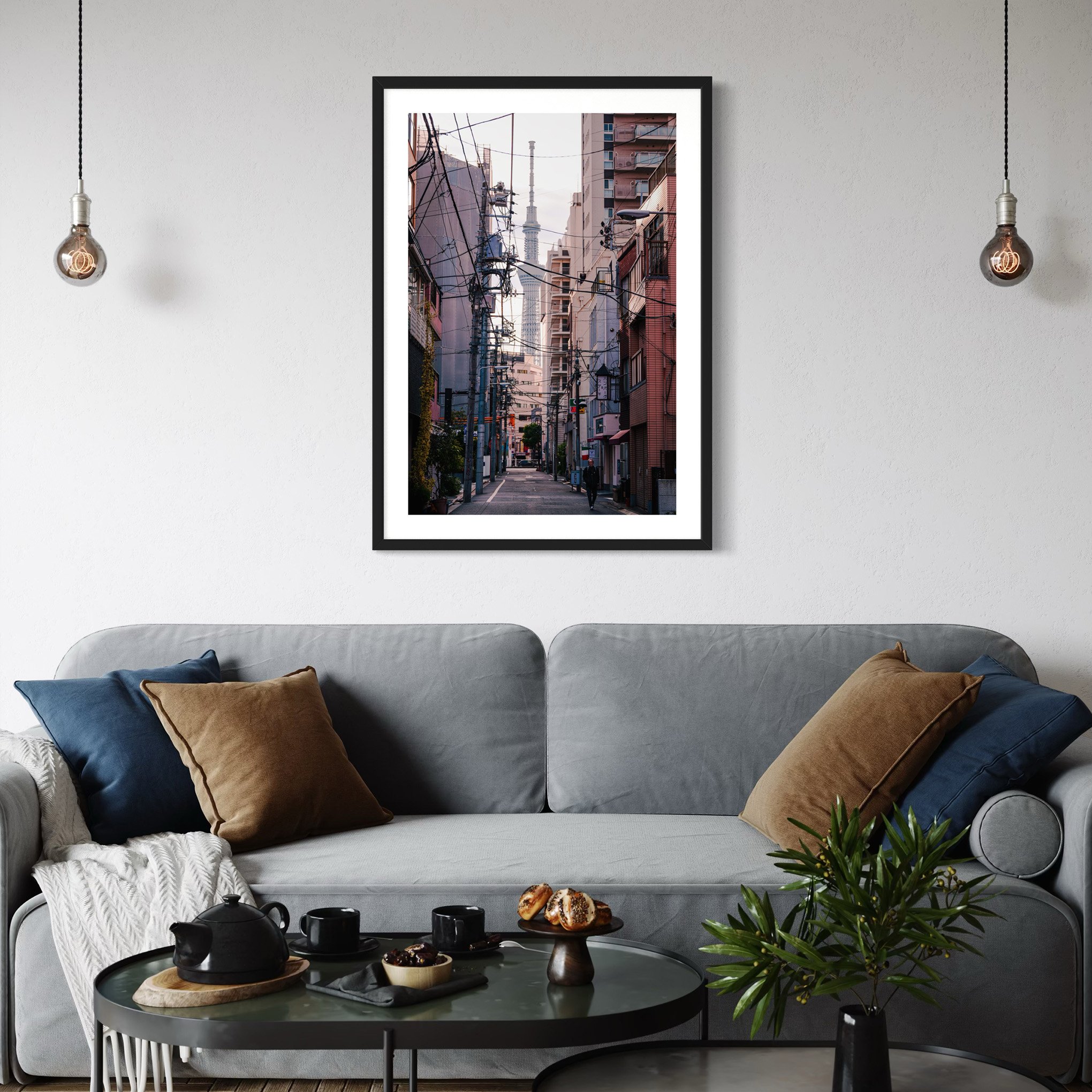 Tokyo Skytree street photography print styled above a grey sofa in a modern living room with soft neutral tones and hanging pendant lights.