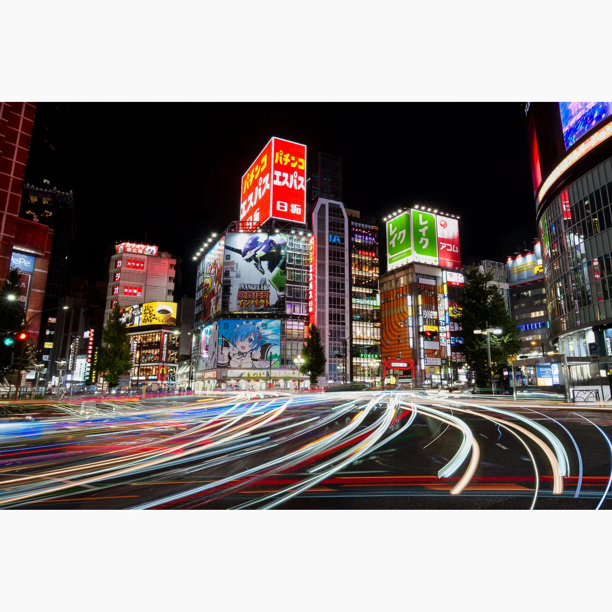 Long-exposure photograph of Shinjuku, Tokyo at night, capturing neon billboards, illuminated commercial buildings and intersecting traffic light trails.