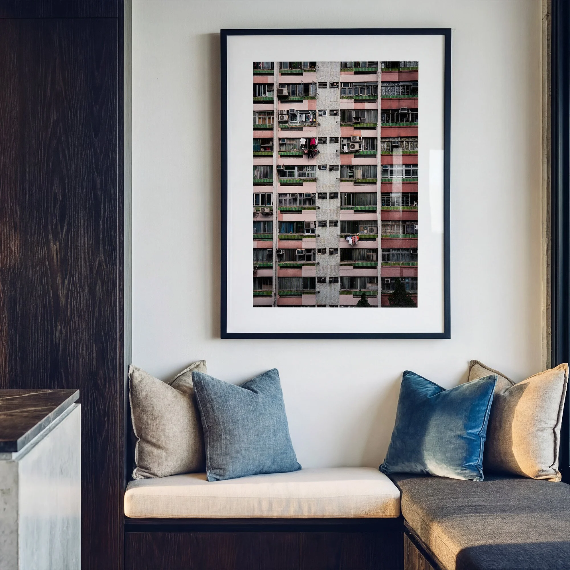 Hong Kong architecture photography print featuring a pink residential apartment façade, displayed in a black frame above a contemporary window seat with blue cushions.