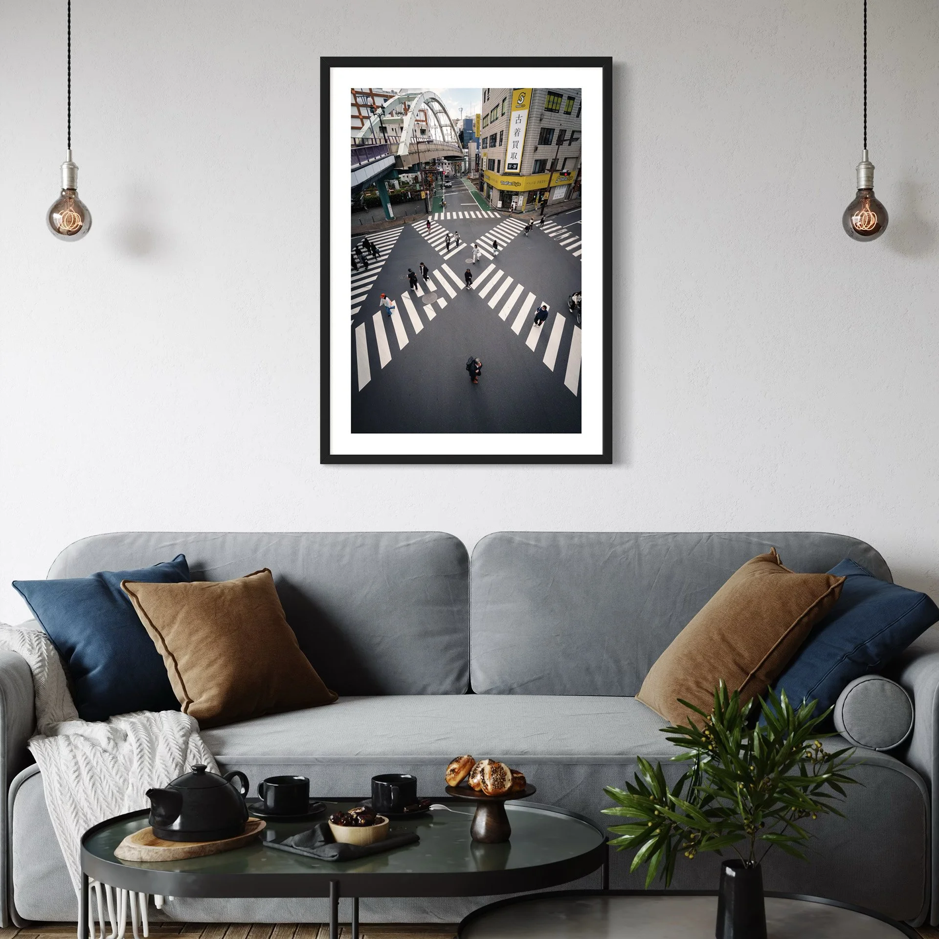 Framed urban photography print of a Tokyo intersection displayed above a grey sofa in a contemporary living room with warm neutral furnishings.