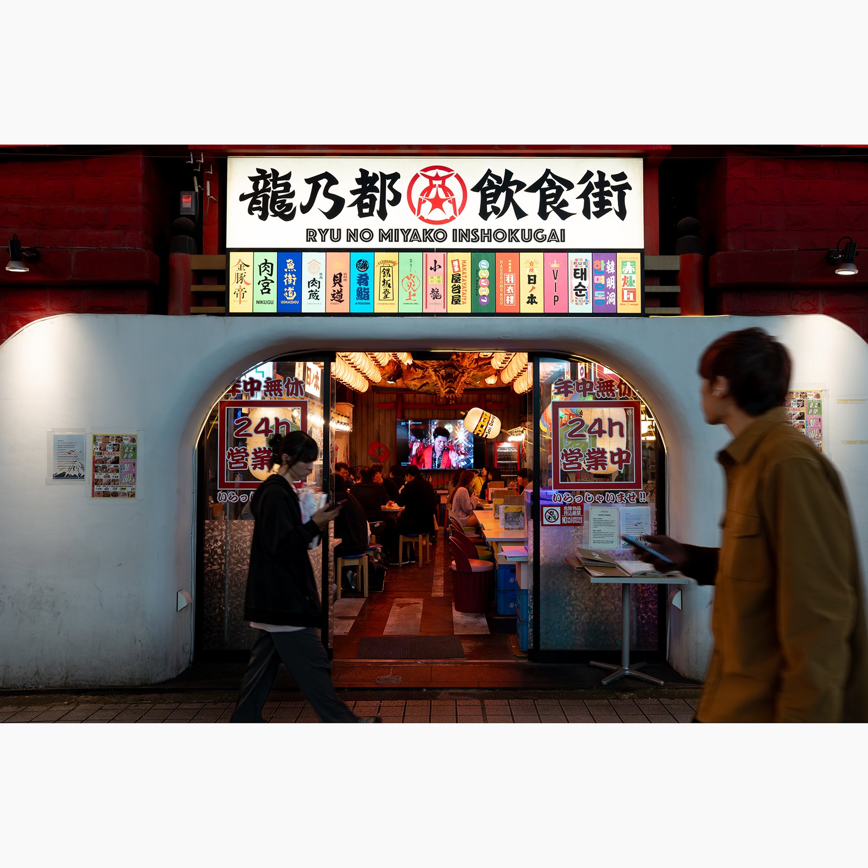 Tokyo street photograph of the Ryu No Miyako dining street entrance, with illuminated Japanese signage and pedestrians passing in front.