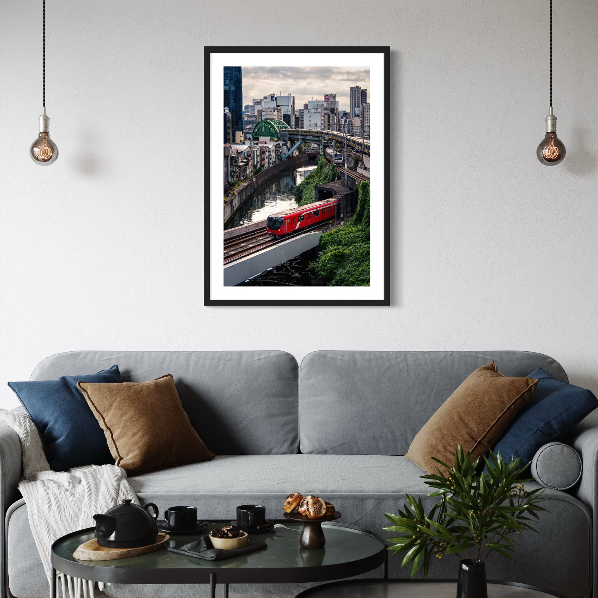 Framed Tokyo train print above a grey sofa in a contemporary living room.