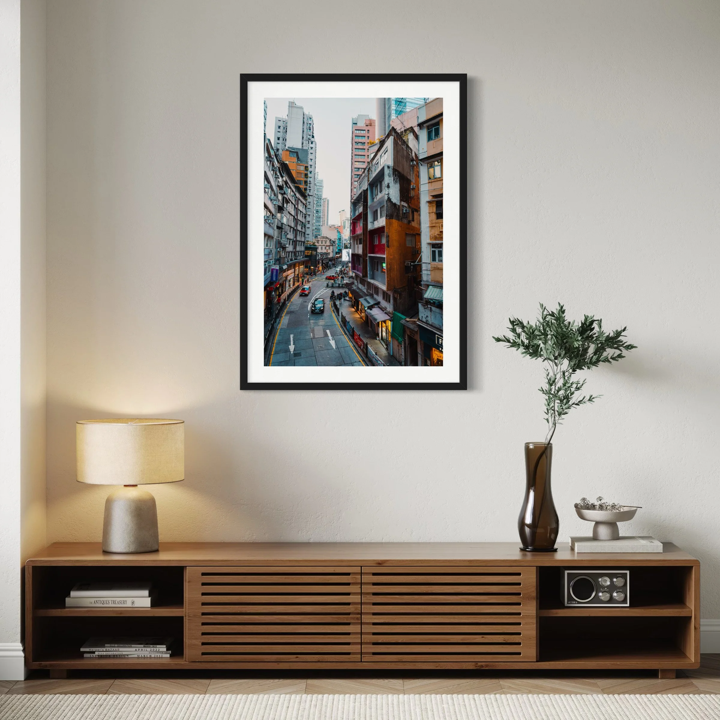 Framed Hong Kong urban photography print displayed above a wooden slatted sideboard in a modern neutral interior with warm lighting.