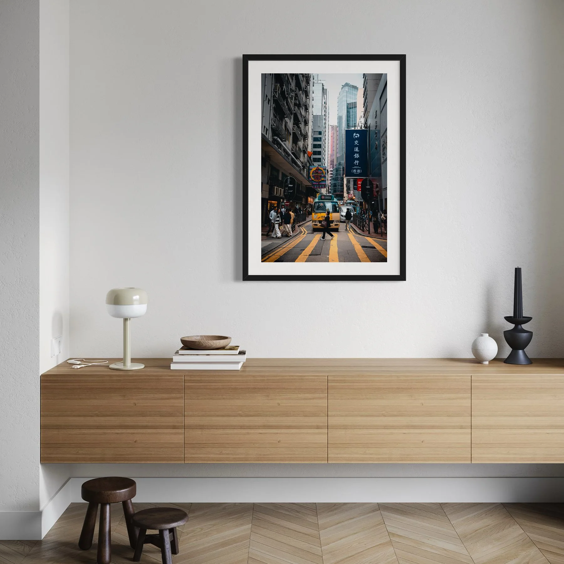 Modern interior with a floating wooden sideboard and framed Hong Kong urban photography print above, showing a yellow minibus moving through narrow city streets.