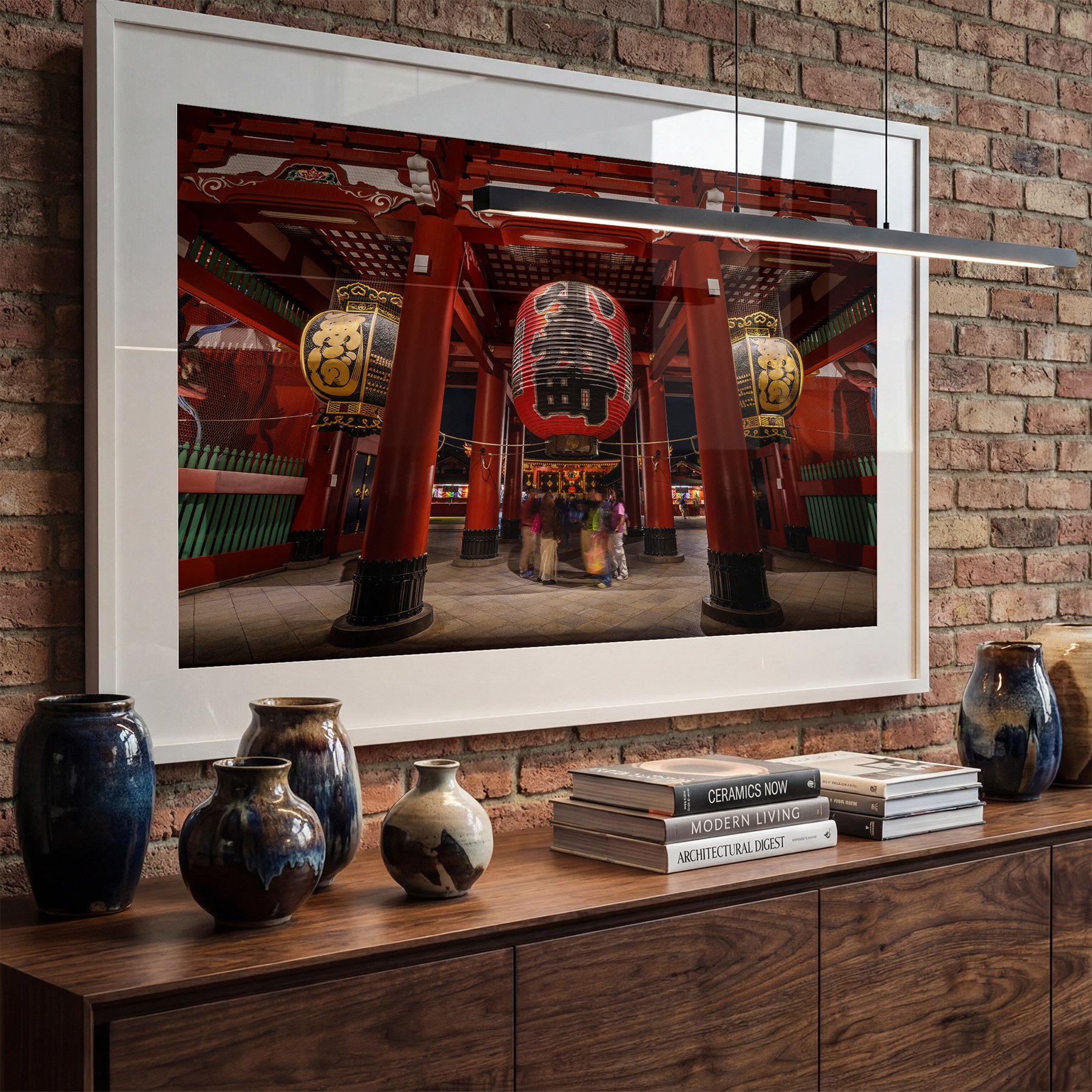 Tokyo temple photography print featuring the lanterns and red architecture of Sensō-ji, displayed in a white frame above a timber sideboard on an exposed brick wall.