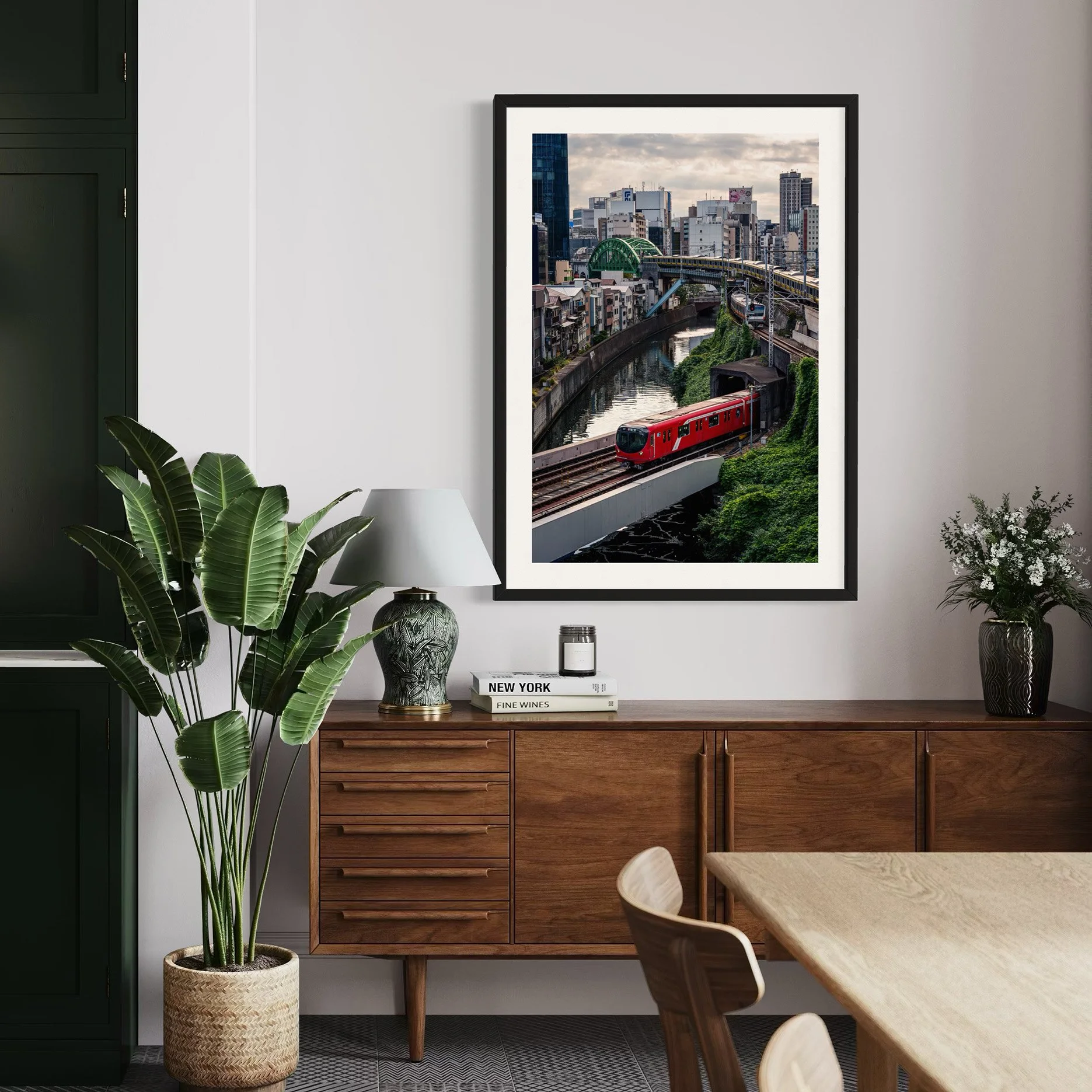 Framed Tokyo train print above a walnut sideboard in a modern dining space.