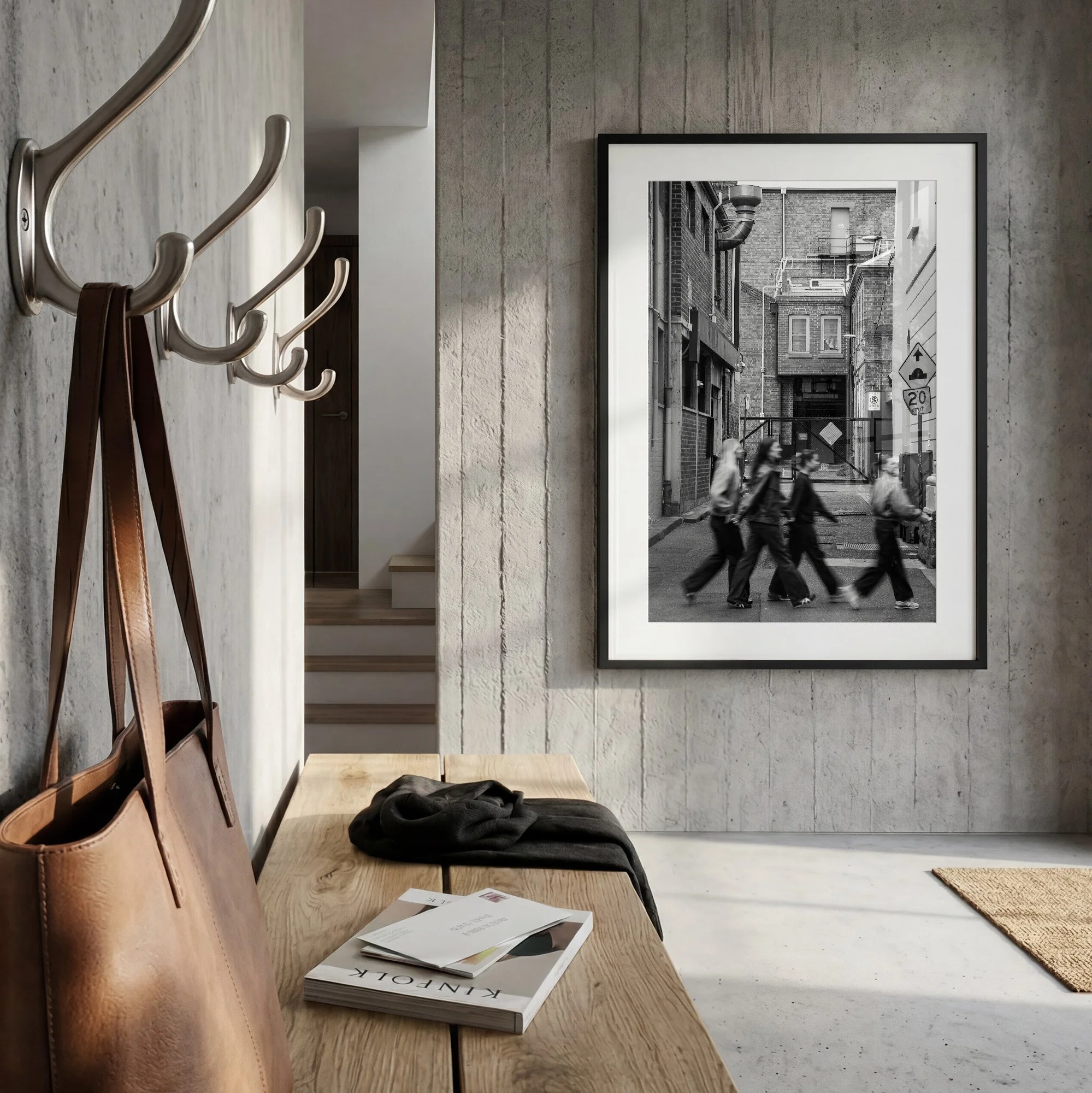 Black and white Melbourne street photography print displayed in a black frame with white mat in a contemporary concrete entryway with timber bench.