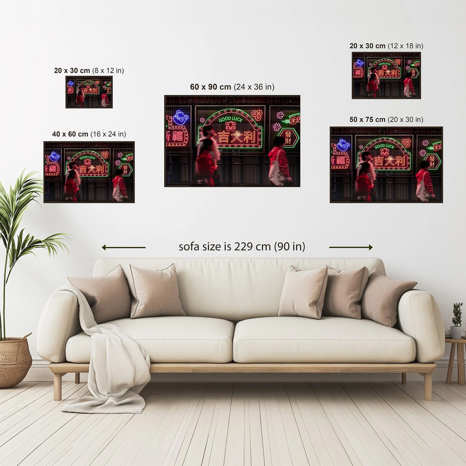 Wall art size comparison guide showing available framed print sizes above a neutral sofa, with dimensions in centimetres and inches for scale reference.