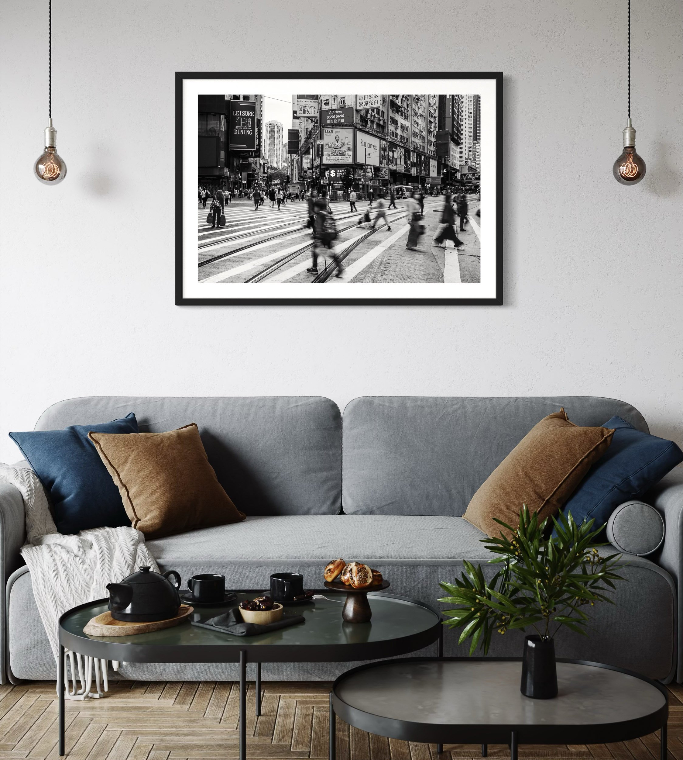 Framed black and white Hong Kong city street photograph displayed above a modern grey sofa in a contemporary living room.
