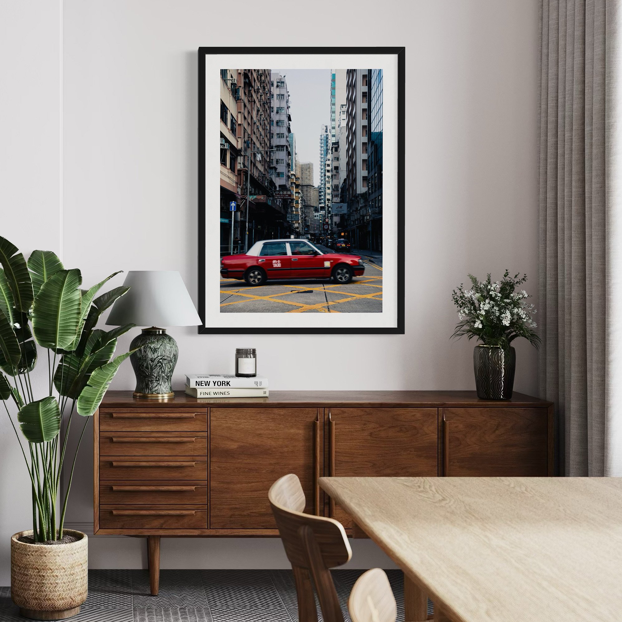 Hong Kong Taxi Rush print displayed above a wooden sideboard and dining table in a warm modern interior.