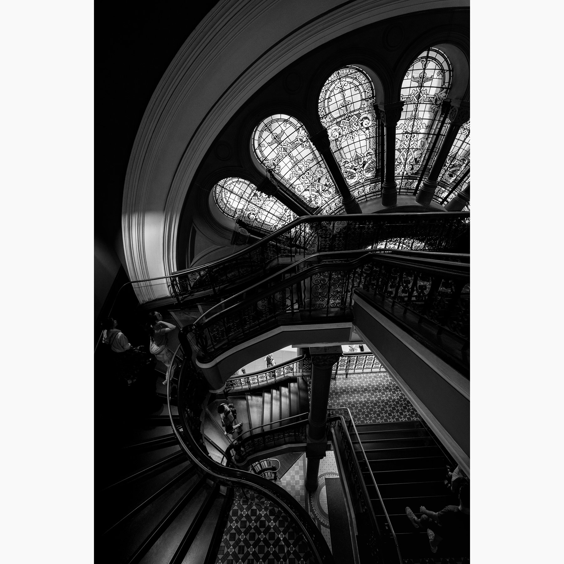 Black and white photograph of the Queen Victoria Building grand staircase featuring ornate stained glass windows and sweeping staircases.
