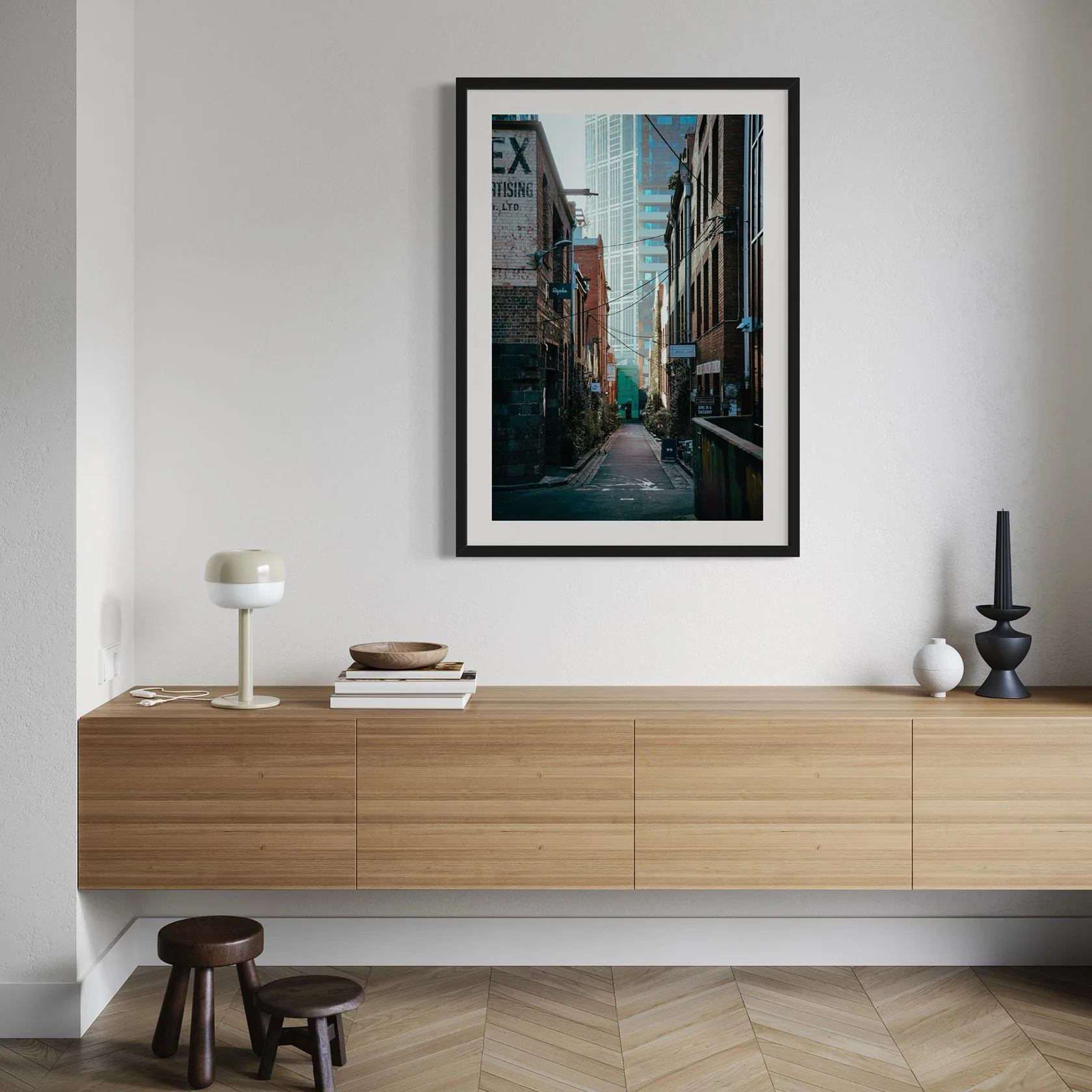 Framed Melbourne alleyway print hanging above a floating timber sideboard in a modern minimalist interior.