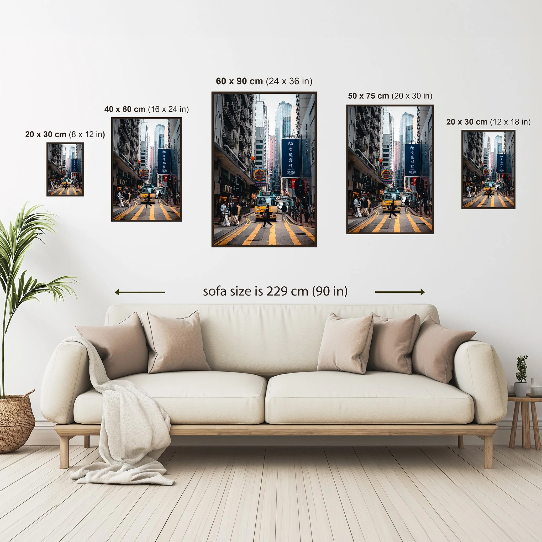 Wall art size comparison guide showing available framed print sizes above a neutral sofa, with dimensions in centimetres and inches for scale reference.