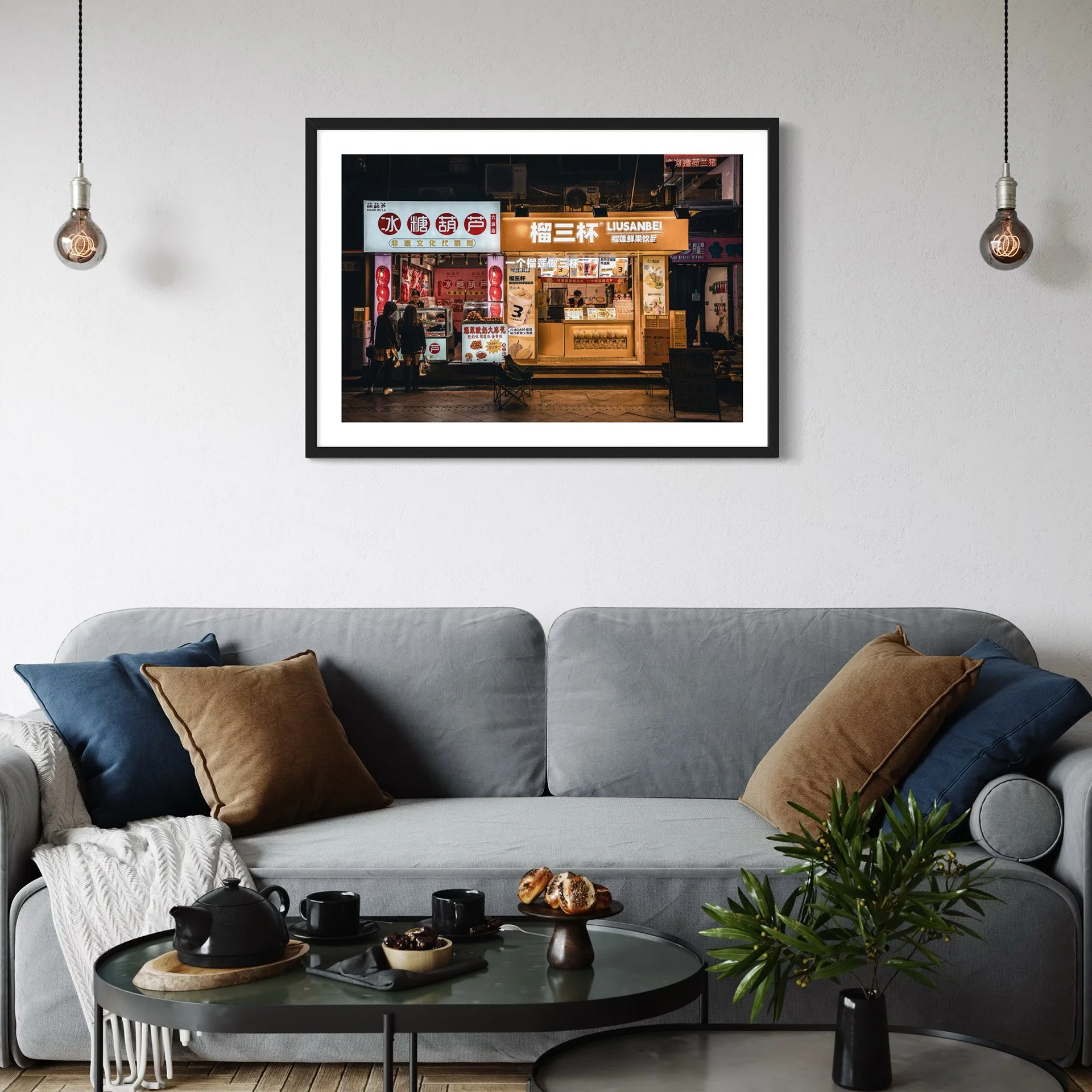 Urban night photography print from Guangzhou displayed above a grey sofa in a modern living room with soft lighting and minimalist decor.