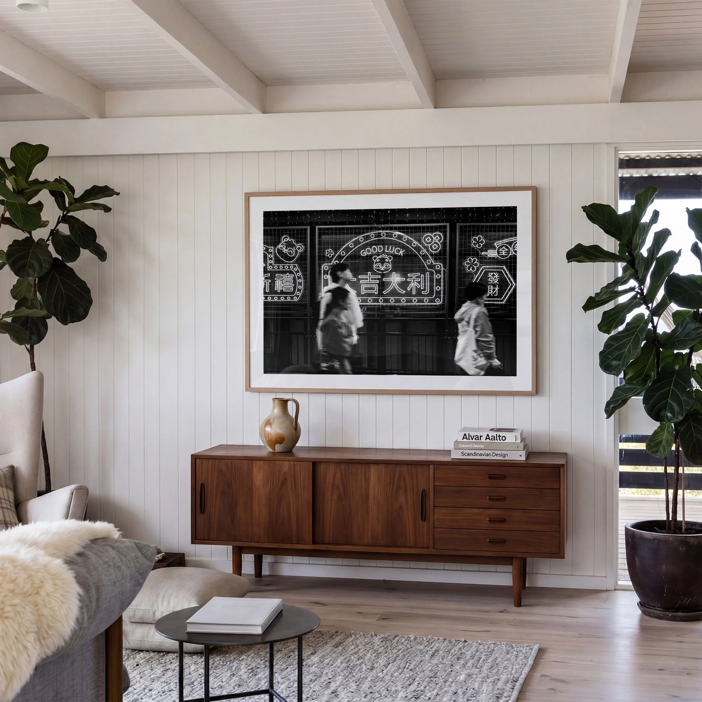 Hong Kong black and white street photography print featuring illuminated signs and blurred pedestrians, displayed in an oak frame above a timber sideboard in a contemporary living room.